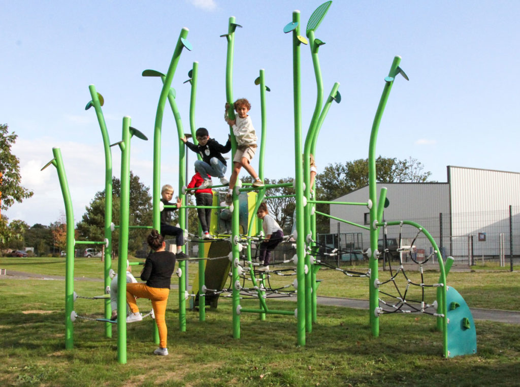 Children climbing and balancing on a tall green nature-inspired rope and pole playground frame.